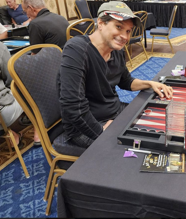 Tommy Tallarico assis sur deux chaises pour jouer au backgammon